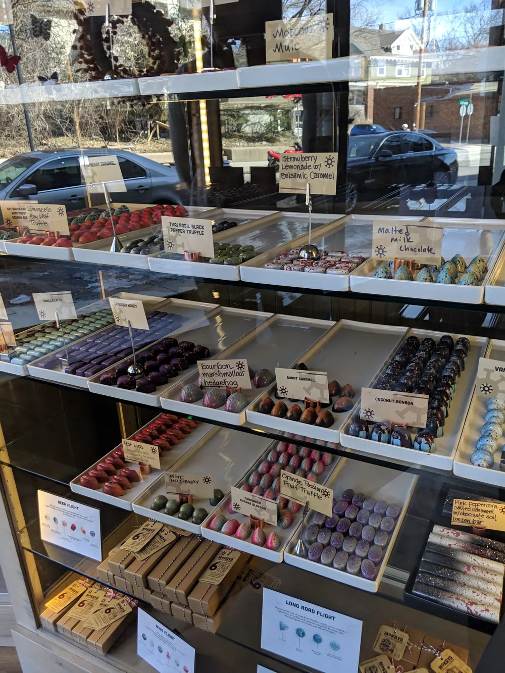 Mokaya gift boxes and flight packaging with bonbons behind glass.