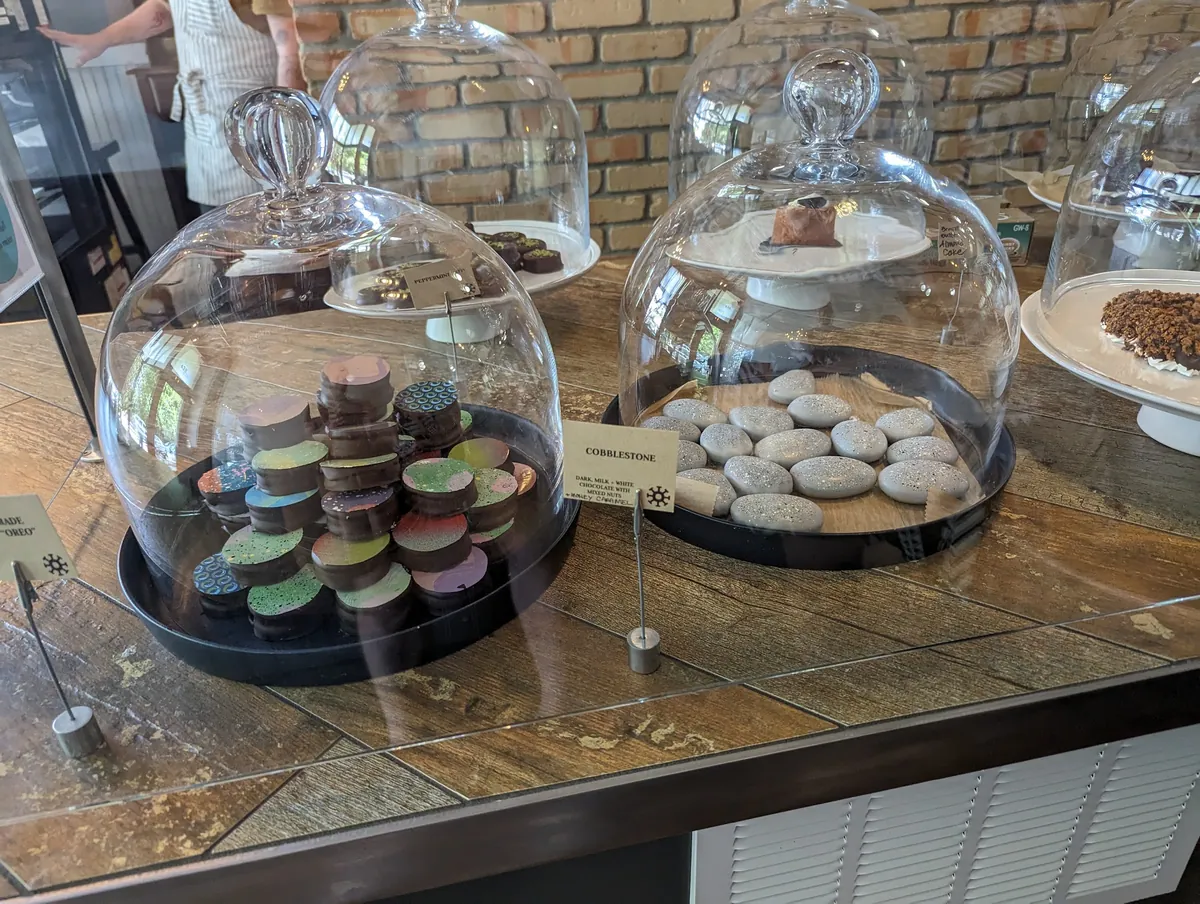 Glass cloche domes of Cobblestone and Oreo-style chocolates on the counter.