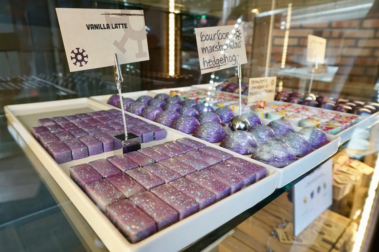Purple and teal galaxy-speckled Vanilla Latte and Bourbon Marshmallow Hedgehog bonbons glowing in Mokaya's case.